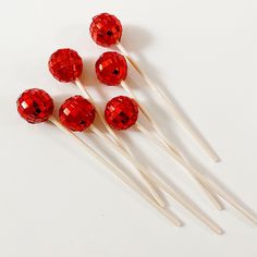 four red lollipops sitting on top of each other next to toothpicks