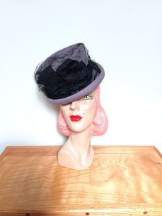 A sassy vintage 1940's tilt topper hat! Fashioned in soft gray felt, fabulous styling! Featuring a tall, indented crown and a rolled brim. A black taffeta ribbon encircles the crown and forms two beautiful bows at the center with a full-face veil. (The veil was gently rolled up for photos) The hat measures approx. 8.5 inches across. The elastic band keeps the hat in place on the wearer. The interior is lined with a grosgrain band. Labeled New York Creation. A divine tilt topper!   Please note the color may vary depending on your monitor   Designed to fit most head sizes due to the style. Sets atop the head. Size is marked adjustable.  In good vintage condition with wear consistent with age. Some soiling and discoloration to the felt on the underside. A few small moth nips in the felt. The Small Moths, Face Veil, Felt Fedora, Kentucky Derby Hat, The Veil, Dec 30, Derby Hats, Beautiful Hats, Full Face