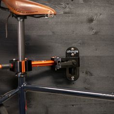 an orange bicycle is mounted to the side of a wooden wall with a black handlebar