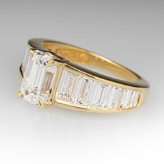 an engagement ring with three baguets and two side stones in yellow gold plated silver