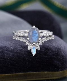 a close up of a ring with a blue stone and diamonds in it on a velvet cushion