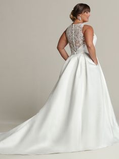 a woman in a white wedding dress with an open back and beaded neckline