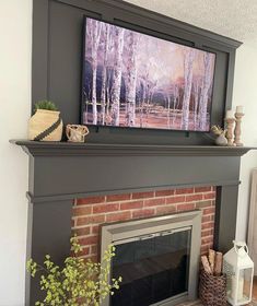 a fireplace with a painting on the mantle and some plants in front of it,