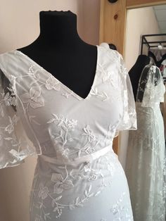 a white wedding dress on a mannequin in front of two other gowns