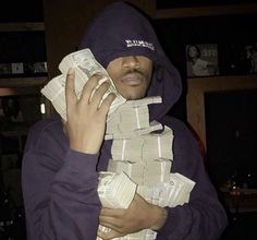 a man in a purple hoodie holding stacks of money