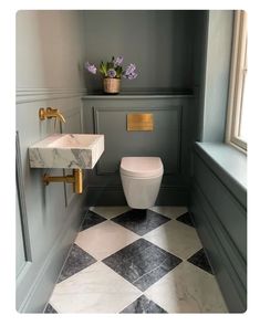 a white toilet sitting next to a sink in a bathroom under a window with flowers on the ledge