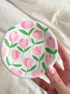 a hand holding a paper plate with pink flowers on it