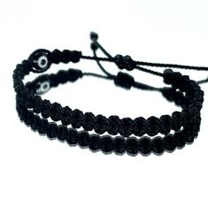 Hand-Made Black String Bracelet With An Evil Eye For Wrist Sizes 6 To 9 Inches, With An Easy To Use Zip Like Function To Fit Your Wrist. Made From High Quality Black String, It Will Be Sure To Last. Wearing An Evil Eye As An Amulet Is Believed To Provide Protection Against Evil Forces. The Evil Eye Meaning Has Symbolism In Almost Every Country In The World And In Every Religion. Each Bracelet Is Carefully Handcrafted And Give Proper Time To Ensure Quality. Trendy Adjustable Bracelet With Black Beads, Trendy Adjustable Black Beads Bracelet, Handmade Black Braided Casual Bracelet, Handmade Black Casual Braided Bracelet, Casual Black Handmade Braided Bracelets, Casual Black Handmade Braided Bracelet, Adjustable Black Beads Evil Eye Bracelet Gift, Handmade Black Wristband For Friendship, Black Minimalist Jewelry With Adjustable Cord