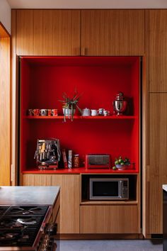 a kitchen with red shelves and wooden cabinets