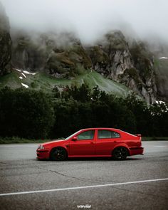 a red car parked in front of a mountain