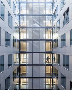 the inside of an office building with lots of windows and people walking through it on their way to work