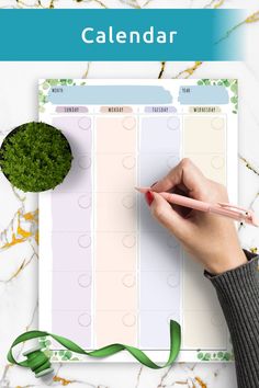 a person writing on a planner with a green plant next to it and the words calendar written