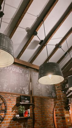 some lights hanging from the ceiling in a room with brick walls and exposed beams on the ceiling