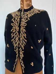 "Elegant black wool cardigan with gold a d clear bead decoration. Black lining, nine metal eyelets closure in the front Armpit to armpit 19\" Neck to hem 20 1/2\" Shoulder seam to shoulder seam 16 1/2\" Great vintage condition SHOP THE STORE:  https://www.etsy.com/shop/BrocanteBedStuy?" Elegant Gold Sweater For Winter, Elegant Gold Winter Sweater, Gold Cardigan For Fall Party, Gold Cardigan For Winter Party, Fitted Gold Cardigan For Fall, Elegant Gold Cardigan For Winter, Elegant Gold Winter Cardigan, Black Embellished Winter Cardigan, Black Embellished Cardigan For Winter