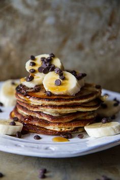 a stack of pancakes topped with bananas and chocolate chips