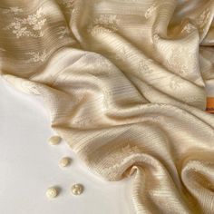 an image of a white cloth with pearls on the bottom and in the middle that is laying down