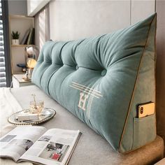 a blue pillow sitting on top of a bed next to a book