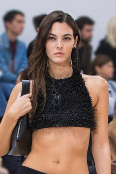 a model walks down the runway in black shorts and a crop top with sequins on it