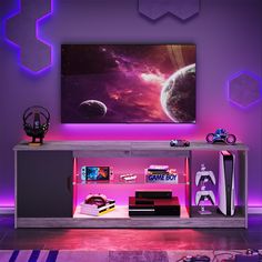 an entertainment center with a large television mounted on it's sideboard in front of a purple wall