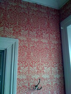 the wall paper in this bathroom is red and white with an intricate design on it