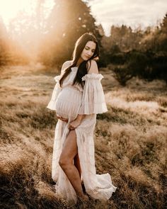 a pregnant woman standing in a field with her hands on her hips and looking at the camera