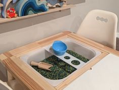 a wooden table with bowls and spoons on it in front of a wall shelf