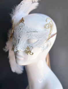 Our women's white laser cut metal masquerade mask, adorned with delicate white feathers and a gold crystal brooch, offers you the opportunity to add a touch of enchanting gold glitter to the mask. Whether you're attending a grand masquerade ball, a themed gala, or simply looking to add a touch of elegance to your attire, this mask ensures you'll be the center of attention. Age Group/Gender - Adult/Women Size/Type - One size fits all adults Mask Color - White Mask Material - Laser cut metal Masquerade Mask With Veil, White Swan Mask, Elegant Gold Masquerade Mask As Gift, Elegant Gold Eye Mask For Masquerade, Elegant Gold Eye Masquerade Mask, Elegant Wedding Masks, Elegant Gold Mask For Carnival, Elegant Gold Masks For Carnival, Elegant Gold Masquerade Mask For Wedding