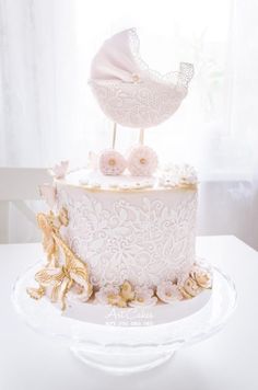 a white cake decorated with pink flowers and a baby carriage topper on a plate