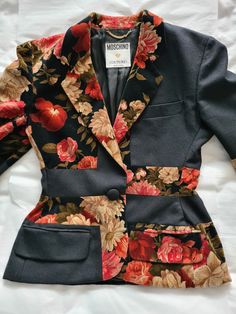 "Moschino Couture by Franco Moschino ca 1990 Blazer style jacket with slightly accentuated hips in black woolen cloth and floral velvet with a chiseled effect, collar with notch lapel, closure with one fabric-covered button (there is one spare button with the fabric tag), two front flap pockets, one chest pocket, cuffs with four fabric-covered buttons (there is one spare inside a pocket), black lining. Brand tag: early 90s black on white \"Moschino Couture !\" with golden heart and golden chain Tailored Floral Print Outerwear For Formal Occasions, Fitted Floral Print Winter Blazer, Fitted Floral Print Blazer For Winter, Chic Floral Print Fall Blazer, Formal Fall Floral Print Blazer, Fitted Floral Print Blazer With Notch Lapel, Winter Floral Print Long Sleeve Blazer, Winter Long Sleeve Floral Blazer, Black Patchwork Blazer For Spring