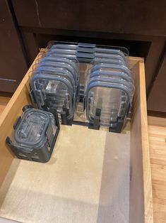 several plastic containers sitting on top of a wooden shelf in front of an oven drawer