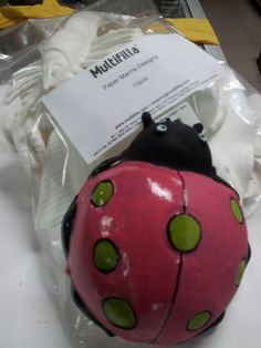 a pink and black ladybug toy sitting on top of a plastic wrapper