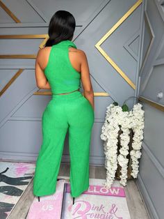 a woman standing in front of a door wearing green pants and a cropped top