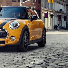 an orange and black mini car driving down the street