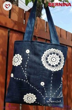 a blue bag with white flowers on it hanging from a wooden fence