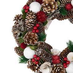 a christmas wreath with pine cones, holly berries and other holiday decorations on white background