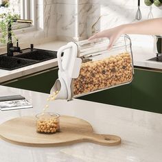 a person pours peanuts into a glass container on top of a cutting board next to a counter