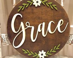 a wooden sign that says grace with flowers and leaves around the letters on top of it