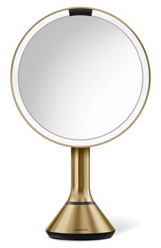 a gold pedestal mirror on top of a metal stand with a black base and a white background