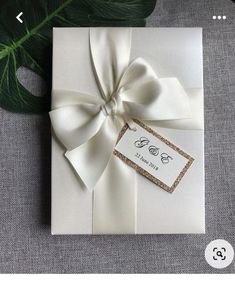 the wedding card is wrapped in white paper with a bow