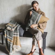 a woman sitting on a bench holding a blanket