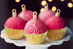 some pink and yellow cupcakes are sitting on a white plate with candles in the background