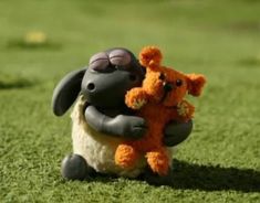 a stuffed animal is holding an orange teddy bear in its arms on the grass outside