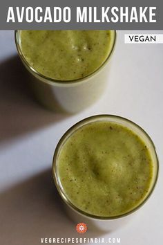 two glasses filled with green smoothie sitting on top of a white table next to each other