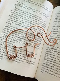 an open book with a wire elephant on it's cover sitting on a table