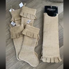 three burlap stockings with ruffles and tags on them sitting on the floor