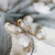 a gold ring with opal stones on it sitting on top of a white flower