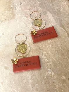 three red tags with gold designs on them sitting on a marble counter top next to each other