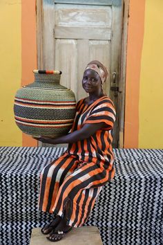 a woman sitting on a bench holding a large vase