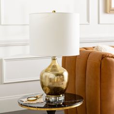 a gold vase sitting on top of a table next to a brown chair and lamp