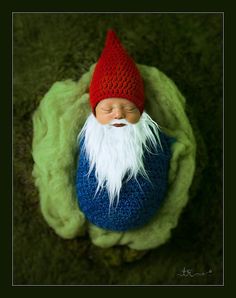 a newborn baby wearing a red, white and blue crocheted gnome hat with long white hair